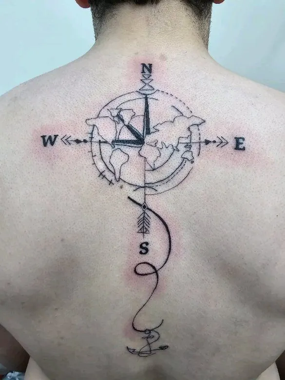 Fijne tattoo van een kompas met windroos en pijl in het midden van de rug