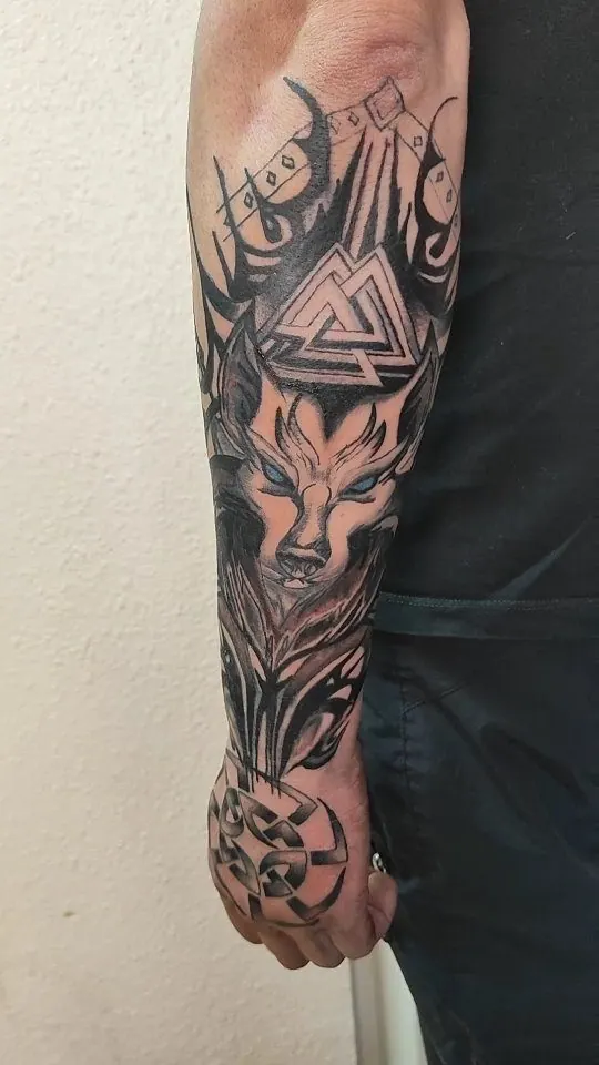 Zwart-grijze sleeve met een wolf, een valknut en geometrische vormen op onderarm en hand